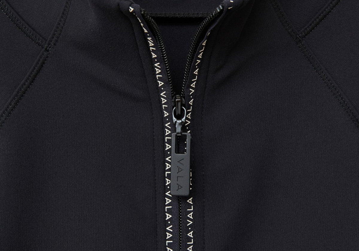 Close-up of the Cloudline Long Sleeve in black with a zipper and VALA branding.