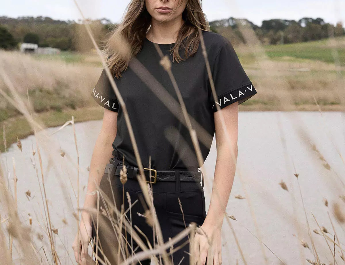 Woman near a dam in a black short sleeve equestrian top